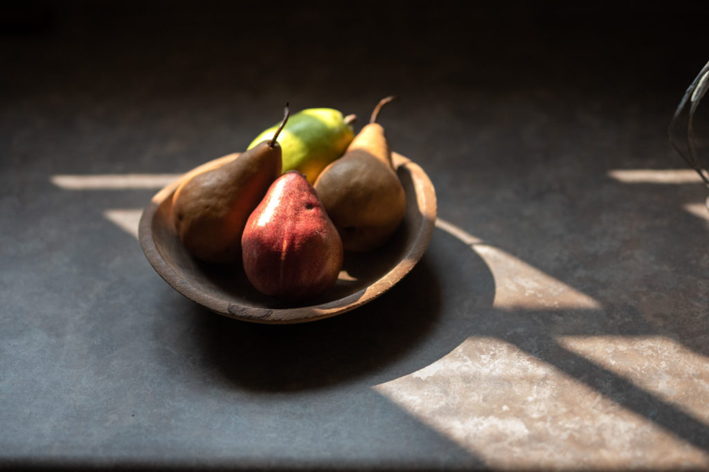 bowl of pears in evening light on a counter