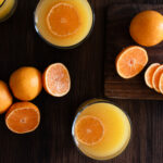 overhead shot of 2 orange adrenal cocktails and cut oranges around it