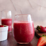 red strawberry drink with strawberries in the background