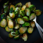 overhead shot of a black plate full of roasted brussle sprouts